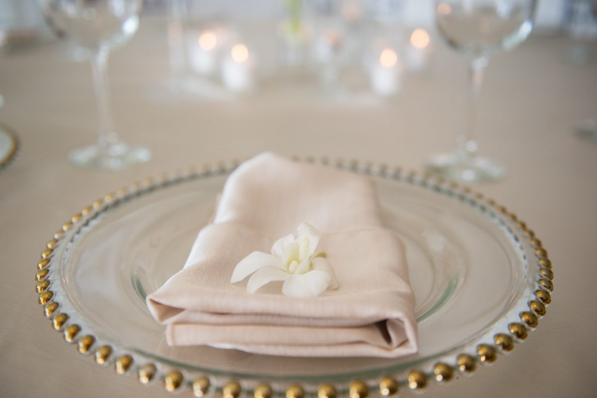 gold rimmed plate with white linen napkin and flower
