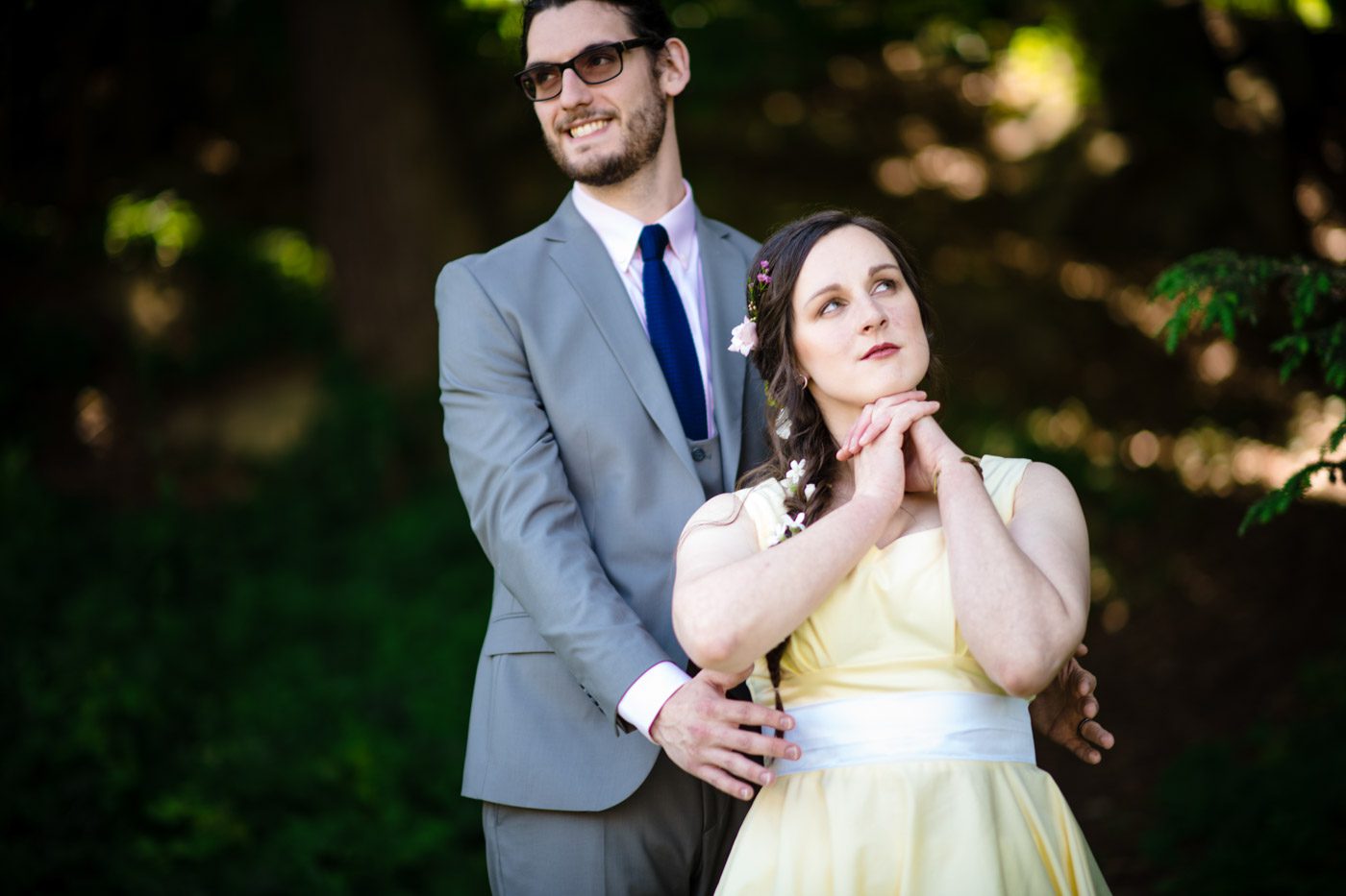 groom-smiling-in-back-of-bride-who-is-daydreaming-in-the-garden
