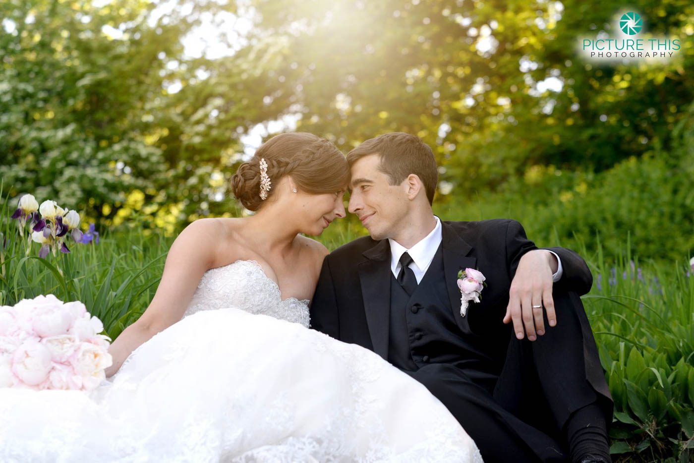 wedding-couple-with-foreheads-together-sitting-in-flower-garden