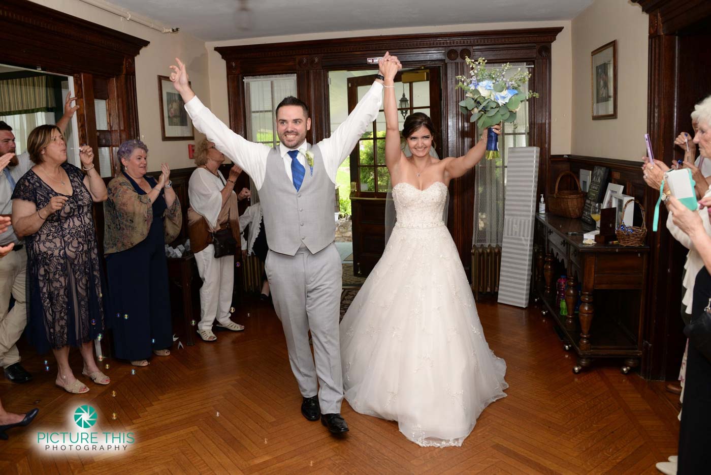 a-late-june-wedding-couple-walking-into-mansion-with-arms-lifted-high