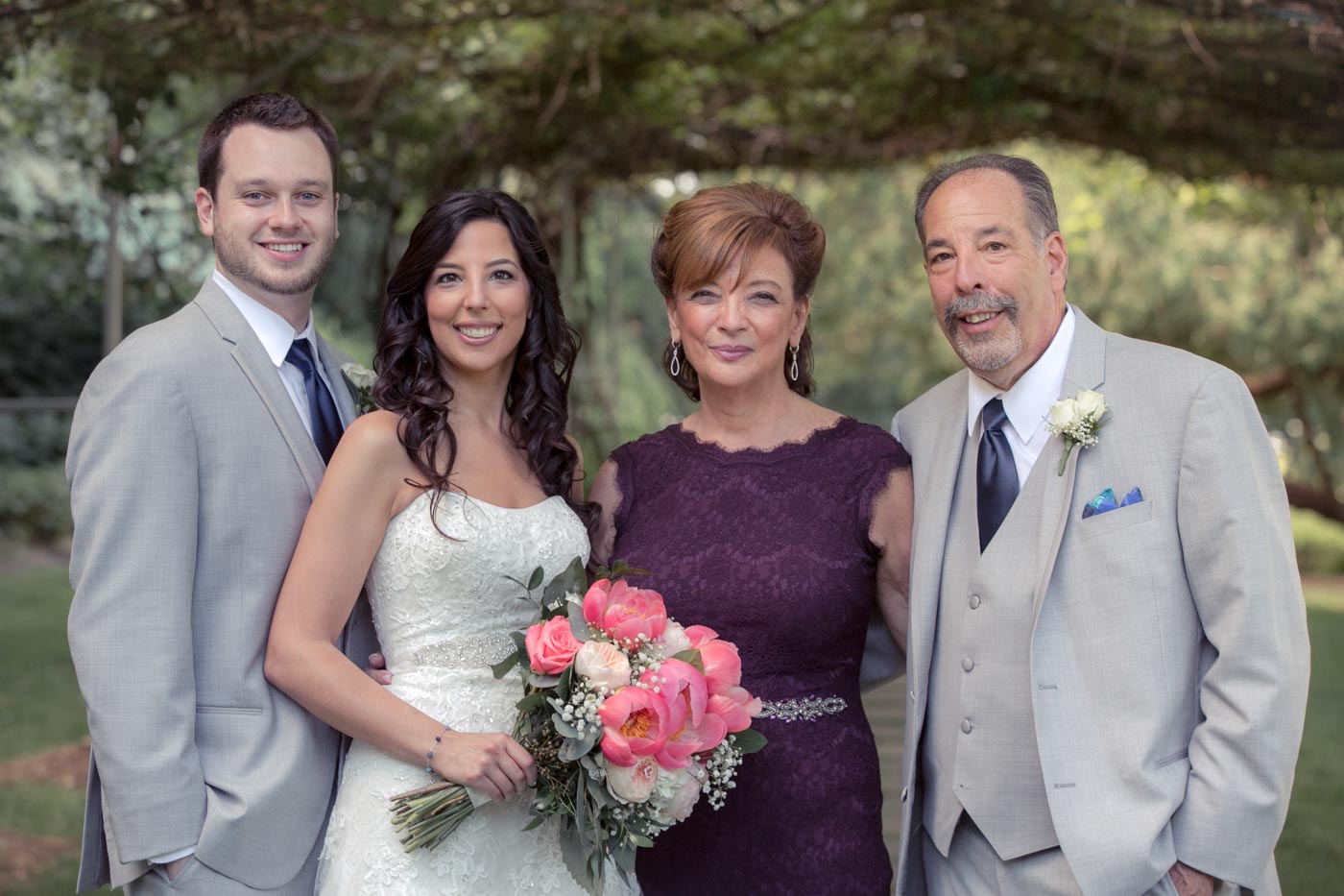 wedding-couple-with-mom-dad-under-grape-arbor