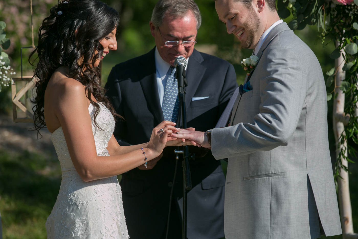 bride-placing-ring-on-grooms-finger-summer-wedding