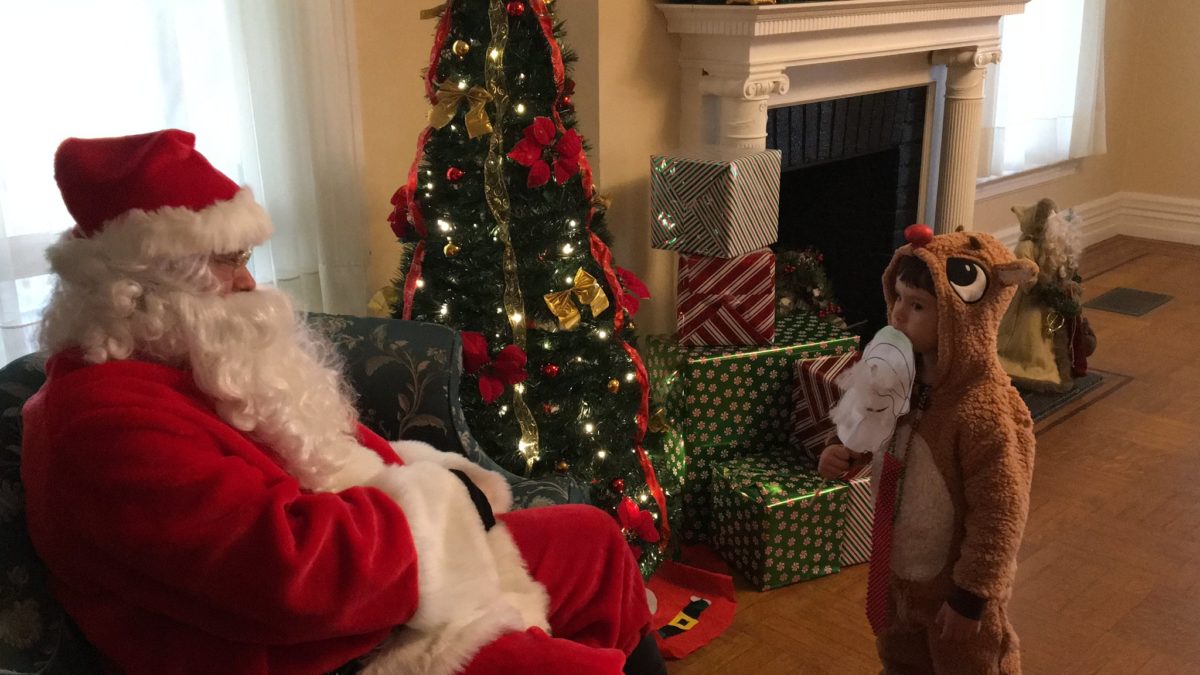 child in rudolf costume talking to santa