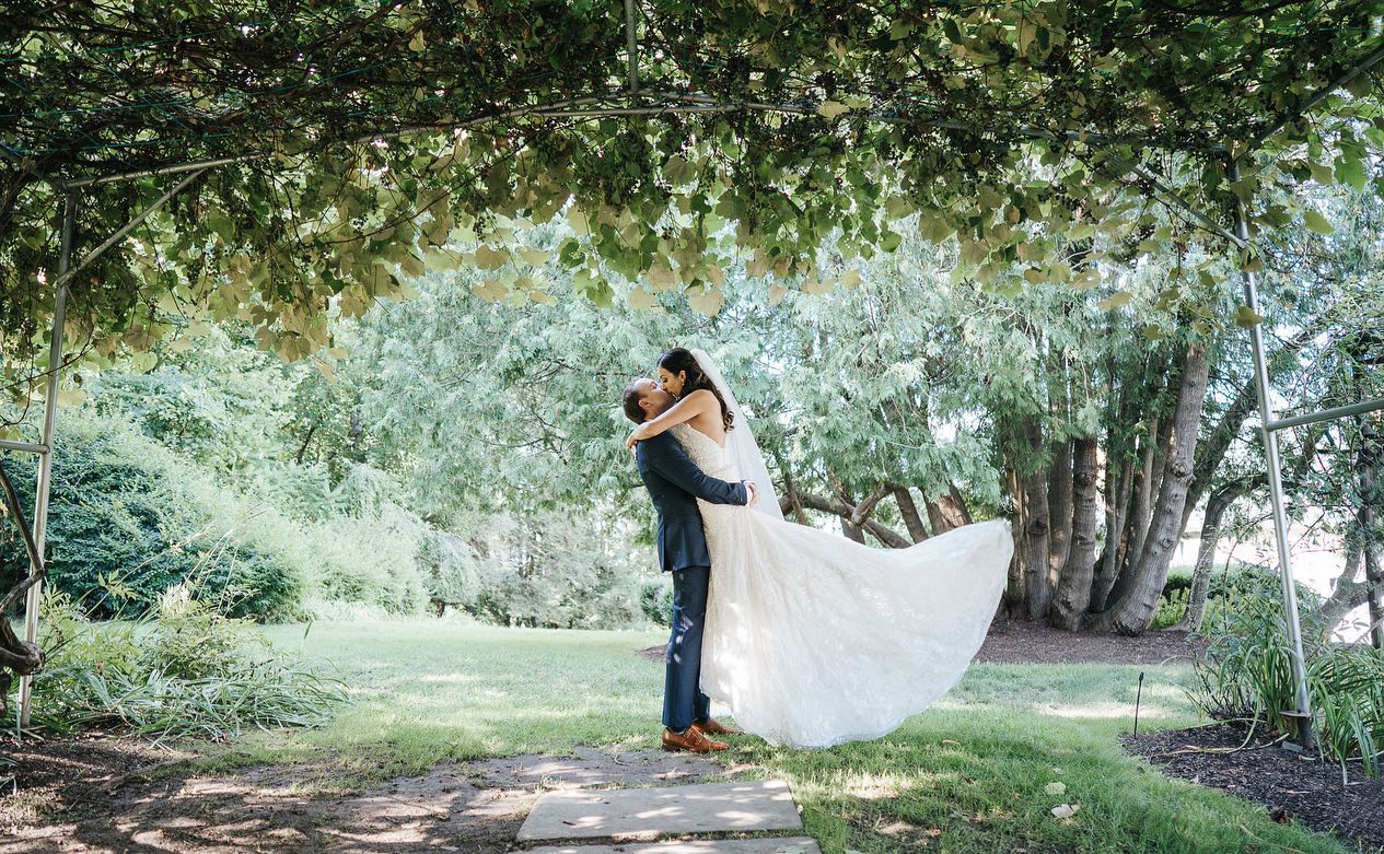 summer-first-look-groom-lifting-bride-in-kiss-in-grape-arbor