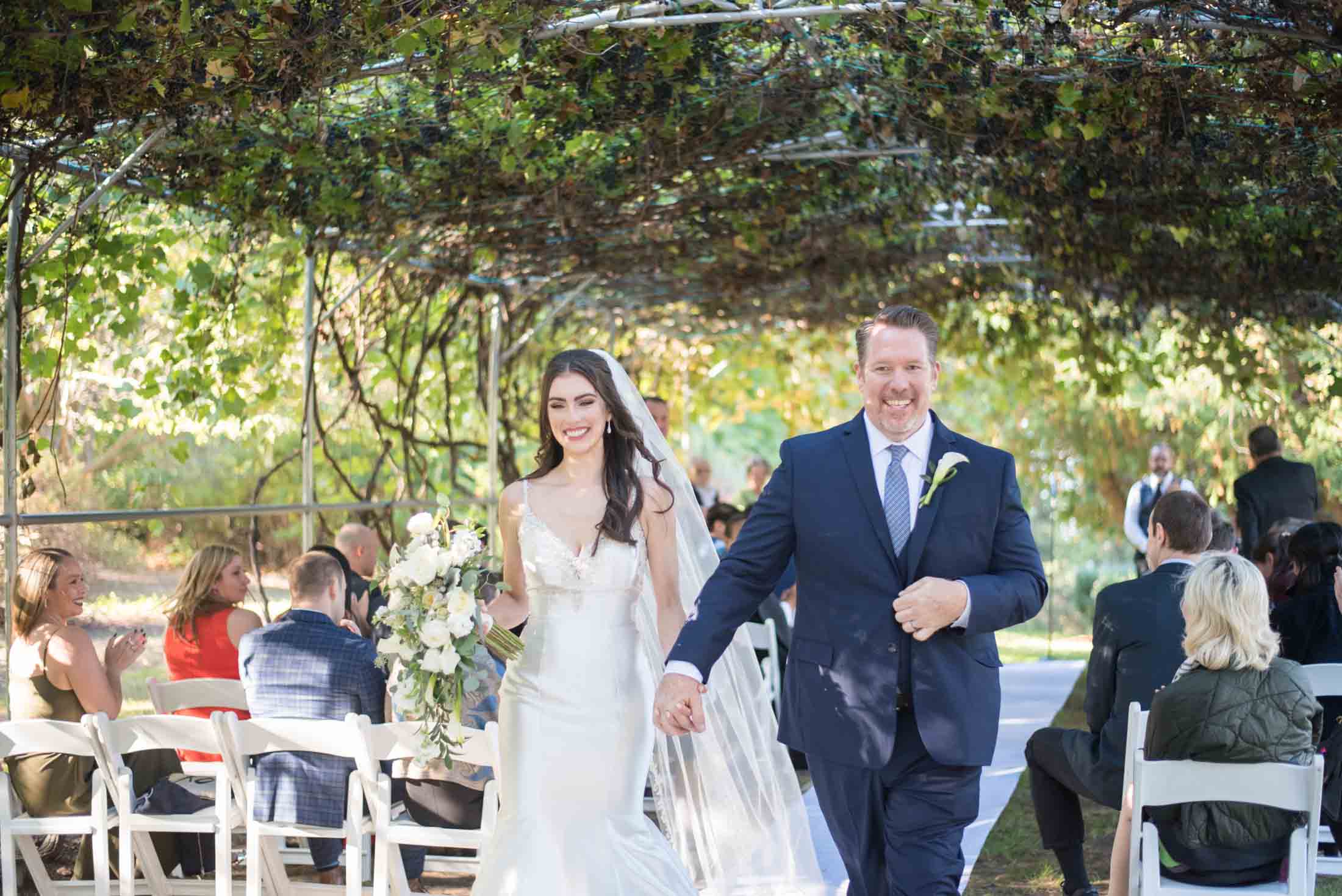 vineyard-style-ceremony-over-bride-groom-walking-down-aisle