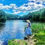 woman in blue dress looking at pond