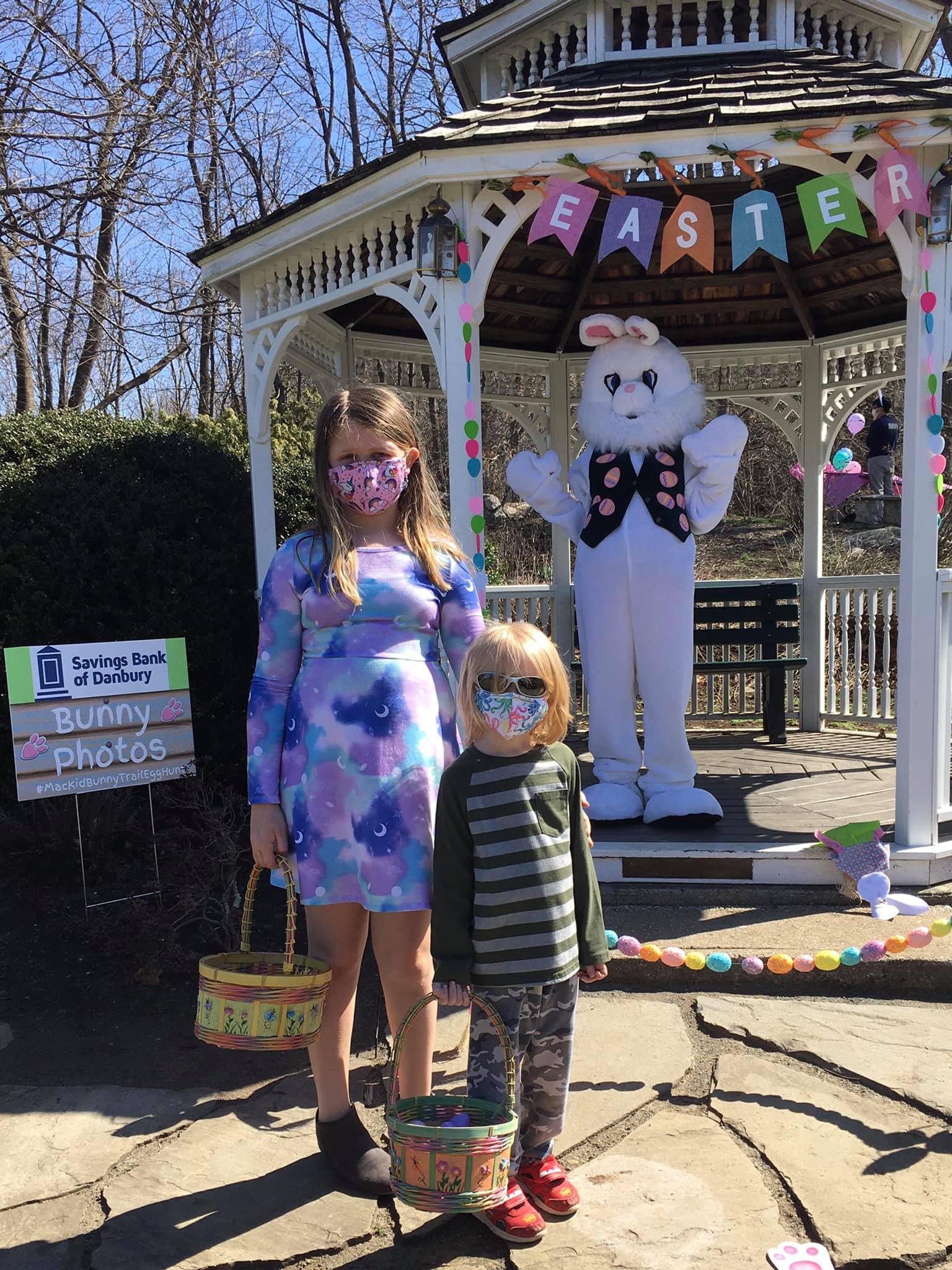 girl and boy standing in front of easter bunny
